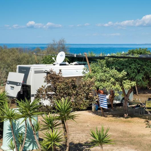 Camper parcheggiato vicino al mare con vista panoramica.