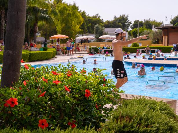 Istruttore guida una lezione di acquagym in piscina all'aperto.