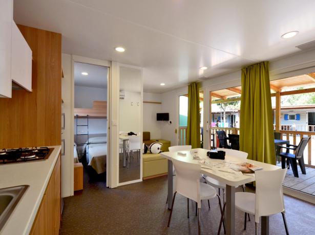 Maison mobile moderne avec cuisine, salon et véranda.
