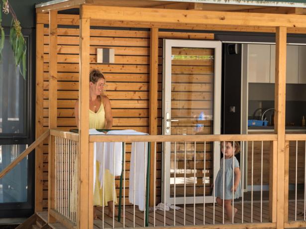Donna e bambina su una veranda in legno.