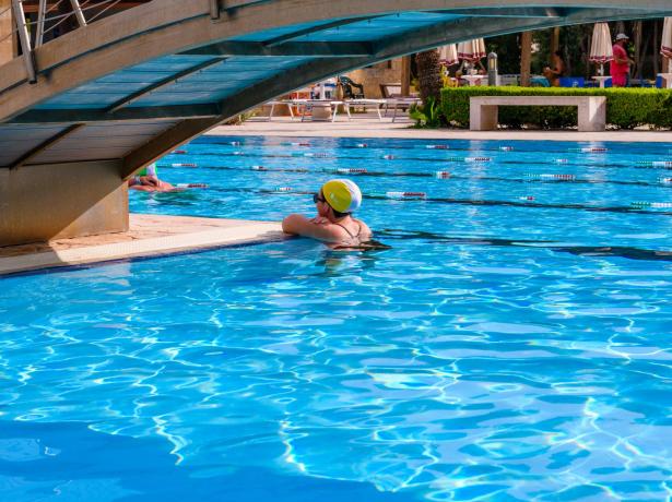 Person im Pool unter der Brücke, sonniger Tag.