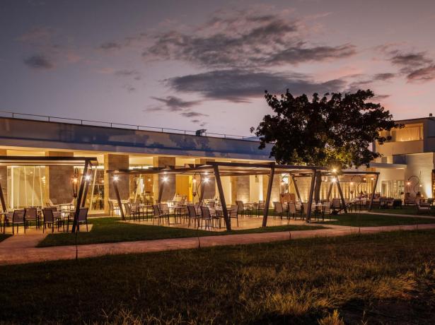 Elegante ristorante all'aperto illuminato al tramonto, con tavoli e sedie moderne.