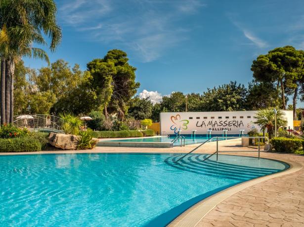 Piscina all'aperto a La Masseria Gallipoli, circondata da palme e giardini.