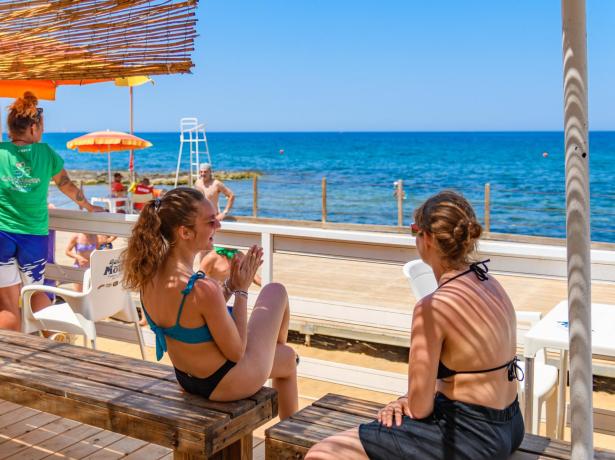 Spiaggia soleggiata, amici felici, mare azzurro, relax estivo.