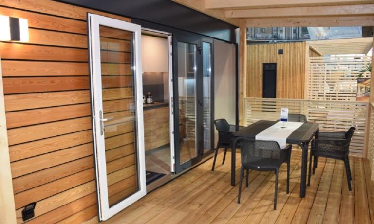 Terrazza moderna in legno con tavolo e sedie.
