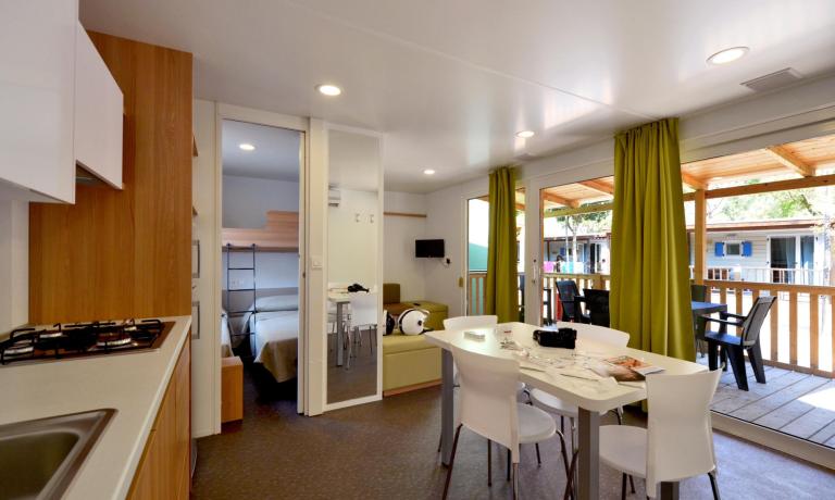 Maison mobile moderne avec cuisine, salon et véranda.