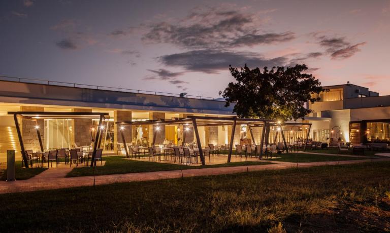 Elegante ristorante all'aperto illuminato al tramonto, con tavoli e sedie moderne.