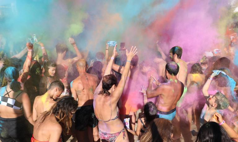 Persone celebrano con polveri colorate in un festival all'aperto.