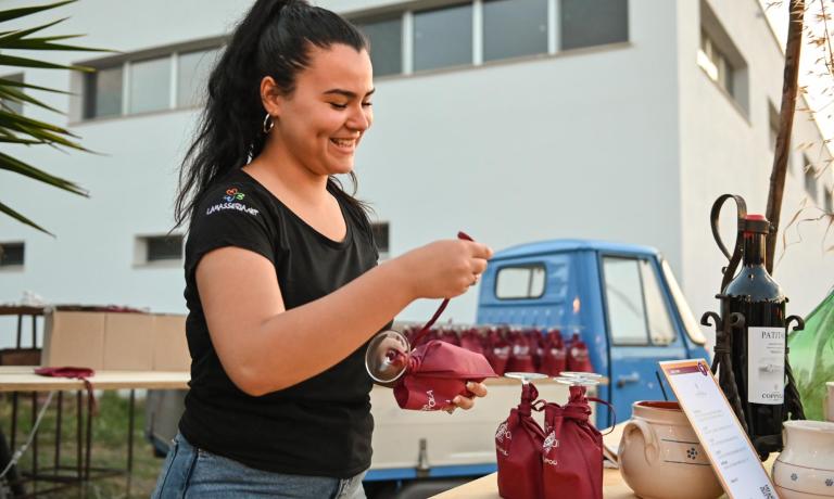Ragazza sorridente prepara calici, atmosfera di festa all'aperto.