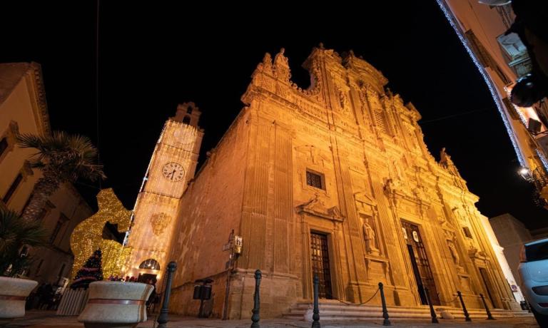 Barockkirche bei Nacht beleuchtet, Uhrturm geschmückt.